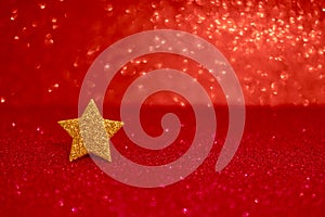 Golden glittering star on red glitter background. Festive abstract red glitter texture background with single golden star.