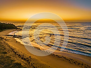 Golden glow sunrise seascape with beach and clear skies