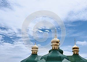 Golden green domes of the church on a background of sky.