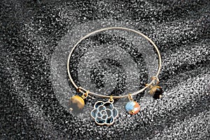 A golden handcrafted bracelet with pearls and spheres on sand