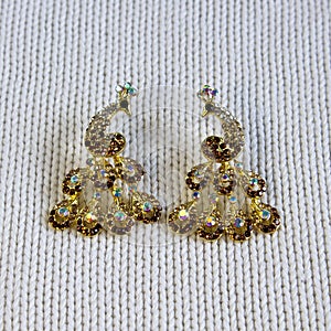 Golden handmade earrings on tinsel on grey textured fabric background