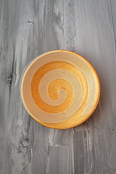 Golden handmade painted wooden plate on grey background