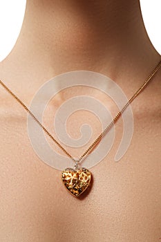 Golden heart pendant. Beauty and jewelry concept. Woman wearing