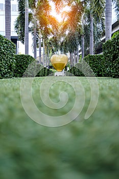 Golden heart shaped sculpture in green garden with sunlight effect at CDC, Crystal Design Center