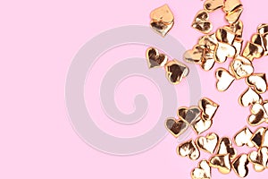 Golden hearts confetti on a pink background.