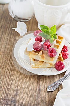Golden homemade fresh waffles for breakfast with cream and raspberries
