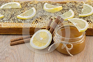 Golden honey in the comb in a jar and yellow lemon