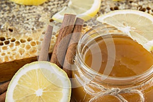 Golden honey in the comb in a jar and yellow lemon