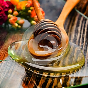 Golden honey on plate and colorful flowers