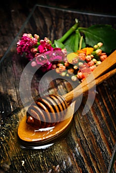 Golden honey on plate and flowers