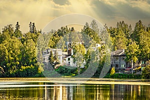 Golden Hour at the lake - Houses on opposite side and trees reflect into water under evening sky