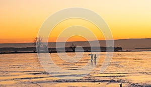 Golden hour People silhouettes walking on the St Lawrence River at the Lachine Canal Montreal in Warm Winter Sunset