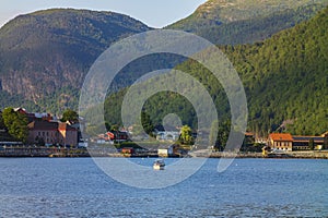 Golden hour at Sogndal, a village Vestland county, Norway near a body of water, shown here with a motorboat