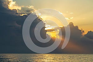 Golden hour, the sun's rays make their way through the clouds above the water surface