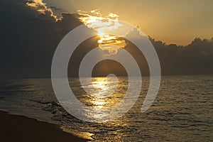 Golden hour, the sun's rays make their way through the clouds above the water surface