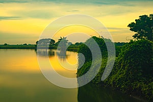 Golden hour during sunrise over the lake with trees in Gresik, East Java. Indonesia.