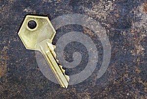 Golden house door key on a rusty metal background