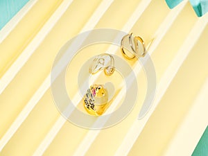 Golden jewelry ring fashion accessories on yellow pastel paper fan background