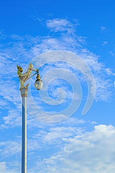 Golden Kinnaree on light pole against blue sky