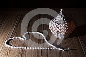 A golden light Ramadhan candle with Islamic white rosary beads o