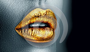 Golden lipstick closeup. Metal gold lips. Beautiful makeup. Sexy lips, bright paint on beautiful model girl`s mouth, close-up