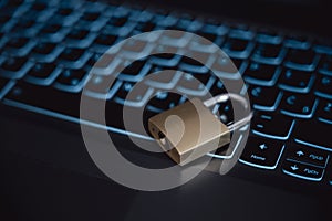 Golden locked padlock lying on a black laptop computer keyboard