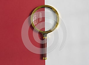 Golden magnifying glass over red and white background. Search tool. SEO concept