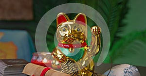 golden Maneki Neko, the Japanese lucky cat figurine, with a raised paw and a red candle