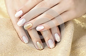 Golden manicure on a golden background. Manicure with white and yellow gold color.