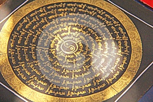 The golden mantra in the circle is painted on black paper and is