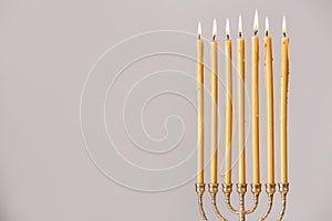 Golden menorah with burning candles on light grey background, space for text