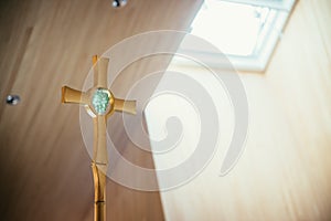 Golden metal crucifix in the church, incidence of light in the blurry background