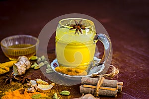 Golden milk or haldi wala dodh with all its dry fruits and spices on wooden surface.