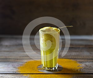 Golden milk, turmeric latte on wooden background. Natural detox beverage with spices.