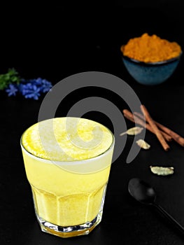 Golden milk with turmeric and other spices on a black background. Traditional drink to support immunity against flu and the common