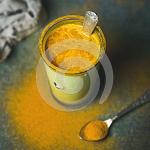 Golden milk with turmeric powder in glass, square crop