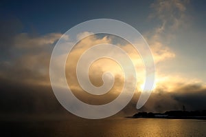 Golden morning mist over the calm water of the lake. Fascinating clouds and fog over the water. Murmansk, Russia