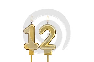Golden number 12 birthday candle on white background