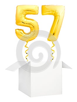 Golden number fifty seven inflatable balloon with golden ribbon flying out of blank white box isolated on white