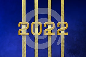 Golden numbers 2022 with ribbons on dark blue background.