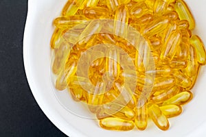 Golden Omega 3 fish oil gel capsules in white mortar on photo