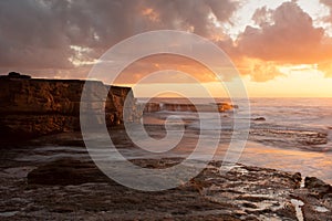 Golden orange light of sunrise across the beach seascape