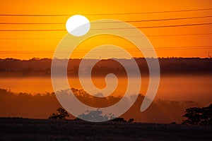 Golden and orange sunrise iluminating a hills and fields