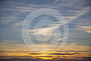 Golden orange sunset and deep blue sky with white feathery clouds contrasting