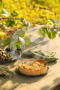 Golden organic healthy crispy pie with artichokes, dried tomatoes and olives on the table