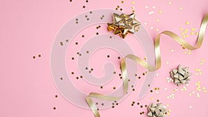 Golden party decorations, curly ribbon and confetti stars on pink background. Festive flatlay style composition for birthday,