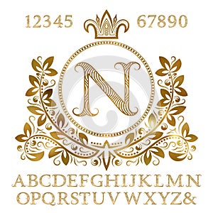 Golden patterned letters and numbers with initial monogram in coat of arms form. Shining font and elements kit for logo design