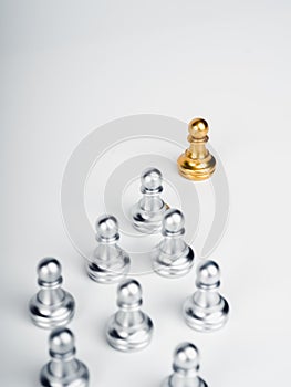 The golden pawn chess piece, leading in front of the group of silver pawn chess pieces.
