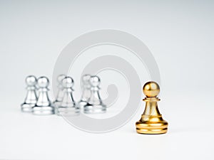 The golden pawn chess piece standing out from the group of silver pawn chess pieces.