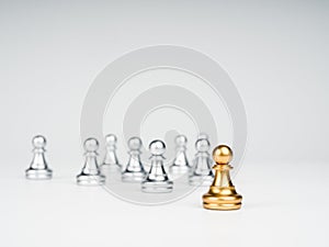 The golden pawn chess piece standing out from the group of silver pawn chess pieces.